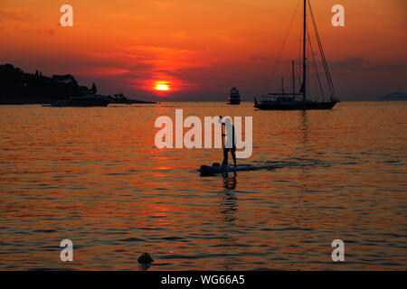 Ein Paddel boarder durch den Sonnenuntergang in Cavtat, eine Stadt an der kroatischen Adriaküste, südöstlich von Dubrovnik. Stockfoto