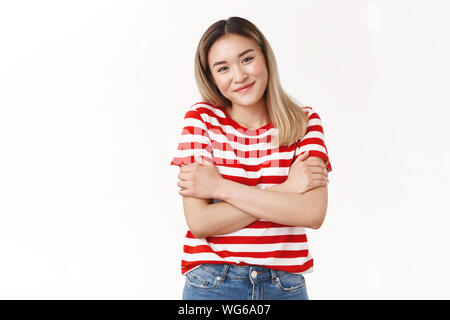 Zarte süße asiatische Frau tragen rote t-shirt gestreift umarmen sich arme Brust Kreuz gehen abends kalt kalt lächelnd Bitte gerne aufhängen Stockfoto