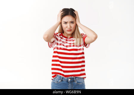 Mädchen können nicht kompliziert unangenehmen Situationen. Verdutzt gedrueckt junge Schülerin harte Entscheidung halten Hände nehmen Kopf stirnrunzelnd intensive Stockfoto