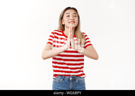 Ziemlich bitte. Cute optimistisch Dumme blonde Asiatin betteln Freund Hand bevorzugen drücken Sie die Handflächen zusammen beten Geste schließen Augen breit grinsend Stockfoto