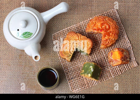 Runde mooncake 8 Körner und gesalzenen Eiern und Squared mooncake rote Bohnen gefüllt, gerührt, das im grünen Tee und gehackte Macadamianüsse serviert mit Kaffee und teap Stockfoto