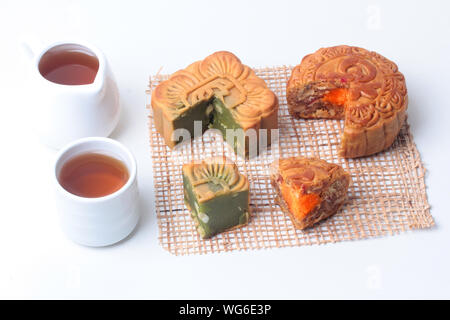 Runde mooncake 8 Körner und gesalzenen Eiern und Squared geformte Mondkuchen, rote Bohnen, gerührt, das im grünen Tee und gehackte Macadamianüsse serviert mit Kaffee und t Stockfoto