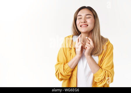 Fröhlich verträumtes Ausschreibung schönen asiatischen blonde Mädchen glücklich lächelnd die Augen schließen, den Kopf anheben, bis die Hoffnung kreuz Finger viel Glück im Vorgriff auf Wunder, Stockfoto