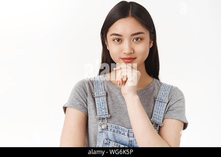 Freundliche motivierte assertive gut aussehende kreative asiatische brünette Frau, Hand, Kinn nachdenklich schmunzelnd bestimmt sehen Kamera Ziel Erfolg denken Stockfoto