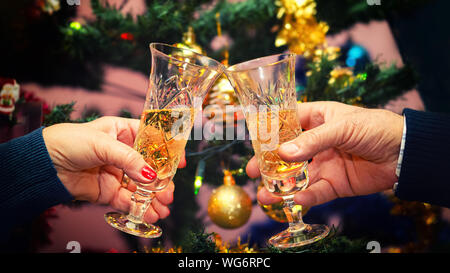 Senior Paar Hände feiern Weihnachten toasten Champagner Wein zu Hause mit geschmückten Weihnachtsbaum im Hintergrund - Winterurlaub Konzept Stockfoto