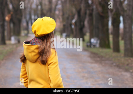 Mädchen in einem gelben Fell und Baskenmütze im Park Herbst Stockfoto