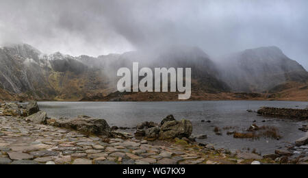 Atemberaubende dramatische Winterlandschaft Bild von Llyn Glyders Idwal und schneebedeckten Bergkette in Snowdonia Stockfoto