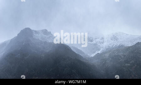 Atemberaubende Moody dramatische Winterlandschaft mountain Bild von schneebedeckten Y Garn in Snowdonia Stockfoto