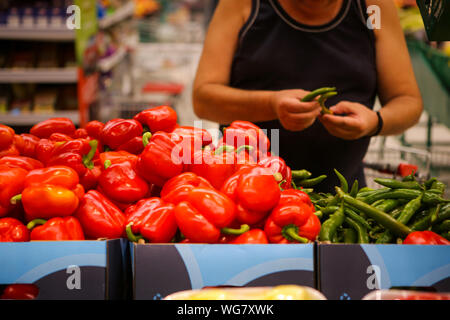 Details eines Mannes die Wahl Hot Paprika (süße Paprika auch auf dem Regal) auf das Obst und Gemüse Gang in einem Geschäft Stockfoto