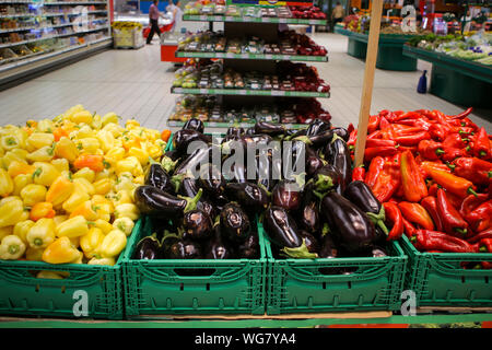 Rote Paprika, Auberginen und gelbe Paprika auf dem Obst und Gemüse Gang in einem Geschäft Stockfoto