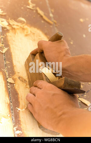 Holz- hand-Ebene. Nahaufnahme des woodworker Hände rasieren mit einem Flugzeug in einer Tischlerei Werkstatt Stockfoto