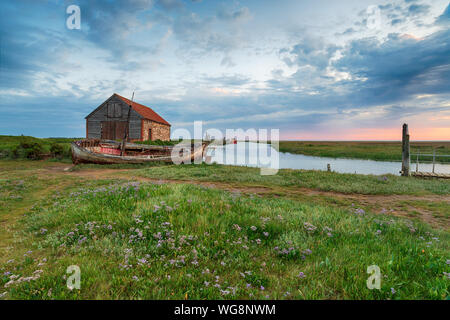 Dramatischer Sonnenaufgang Himmel über dem alten Kohle Scheune Thornham an der nördlichen Küste von Norfolk Stockfoto