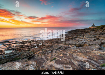 Atemberaubenden Sonnenaufgang über dem Strand von Howick auf der Northumberland Küste mit dem alten Badehaus in der Ferne Stockfoto