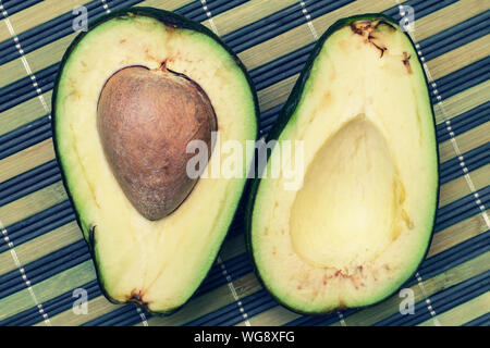 Die beiden Hälften des Avocado auf einem gestreiften Hintergrund. Close-up Stockfoto
