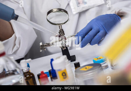 Spezialisierte Polizei unter zeigt Blut im Mikroskop Halterung im wissenschaftlichen Labor zu analysieren, konzeptionell Bild Stockfoto