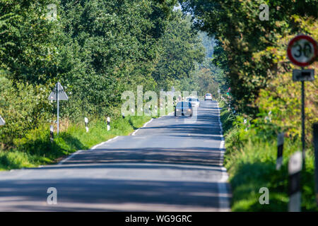 Hude, Deutschland, 30. August 2019: Auf einer Landstraße, ein Rennrad Fahrer von Autos überholt Stockfoto