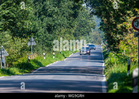 Hude, Deutschland, 30. August 2019: Auf einer Landstraße, ein Rennrad Fahrer von Autos überholt Stockfoto
