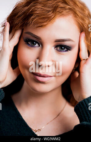 Sehr detaillierte Nahaufnahme Portrait von ziemlich redheah Frau mit perfekt saubere Haut und grüne Augen in die Kamera mit niedlichen Lächeln suchen. Make-up, Haut Stockfoto