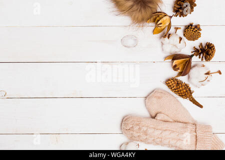Attribute der Winter Floristik, Baumwolle, Kegel und gestrickte Fell pompom mit Handschuhen auf weißem Holz- Tabelle, Ansicht von oben, kopieren. Winter, neues Jahr, Fei Stockfoto