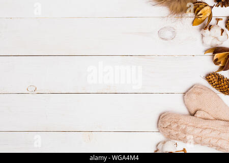 Neues Jahr weiß Holz- Hintergrund für Kopieren. Beige gestrickte Handschuhe, Fell pompom, winter Floristik Attribute in der Tabelle. Winter gemütliche, Flach Stockfoto