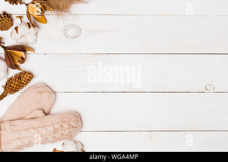 Neues Jahr weiß Holz- Hintergrund für Kopieren. Beige gestrickte Handschuhe, Fell pompom, winter Floristik Attribute in der Tabelle. Winter gemütliche, Flach Stockfoto