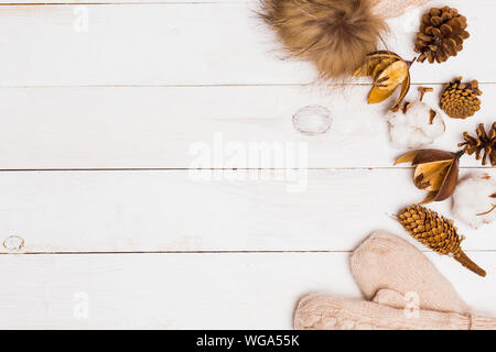 Attribute der Winter Floristik, Baumwolle, Kegel und gestrickte Fell pompom mit Handschuhen auf weißem Holz- Tabelle, Ansicht von oben, kopieren. Winter, neues Jahr, Fei Stockfoto