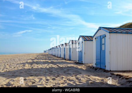 Reihe von weißen und blauen Badekabinen am Strand der Insel Texel in den Niederlanden mit blauem Himmel an einem sonnigen Tag Stockfoto