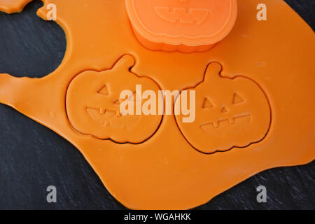 Halloween Cookies backen Konzept mit orange ausgerollten Teig schneiden Sie Cookies in Form von geschnitzten Kürbis Stockfoto