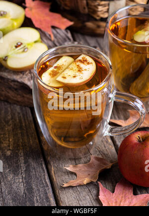 Zwei Tassen Apfelwein mit Apfelscheiben bestreut mit Zimt auf ein rustikales Holz- Oberfläche Stockfoto