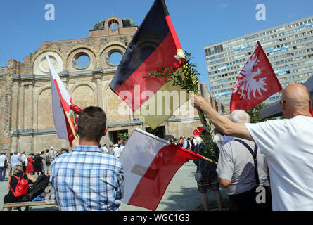 Berlin, Deutschland. 01 Sep, 2019. Menschen mit Deutschen und Polnischen Flaggen nehmen teil an einer Gedenkveranstaltung des deutschen Polen Institut anlässlich des 80. Jahrestages der Angriff deutscher Truppen auf Polen vor der Ruine der Anhalter Bahnhof. Der Deutsche Überfall auf Polen am 1. September 1939 markierte den Beginn des Zweiten Weltkrieges. Quelle: Wolfgang Kumm/dpa/Alamy leben Nachrichten Stockfoto