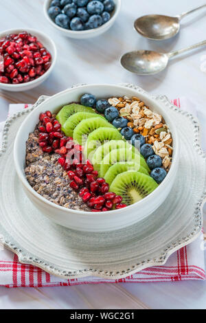 Sommer Porridge mit gemischten Samen und frischem Obst - Blaubeeren, Granatapfel und Kiwi. Gesundes Frühstück. Stockfoto