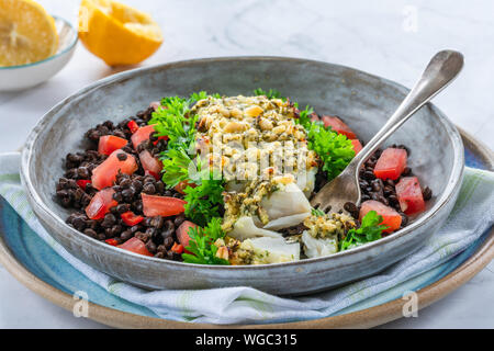 Pesto - verkrusteten Kabeljau mit Puy Linsen und Tomaten in eine Schüssel geben. Stockfoto
