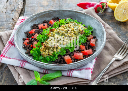 Pesto - verkrusteten Kabeljau mit Puy Linsen und Tomaten in eine Schüssel geben. Stockfoto
