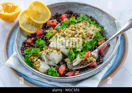 Pesto - verkrusteten Kabeljau mit Puy Linsen und Tomaten in eine Schüssel geben. Stockfoto
