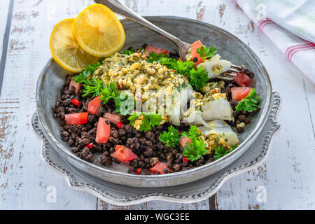 Pesto - verkrusteten Kabeljau mit Puy Linsen und Tomaten in eine Schüssel geben. Stockfoto