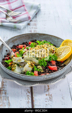 Pesto - verkrusteten Kabeljau mit Puy Linsen und Tomaten in eine Schüssel geben. Stockfoto