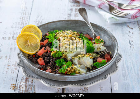 Pesto - verkrusteten Kabeljau mit Puy Linsen und Tomaten in eine Schüssel geben. Stockfoto