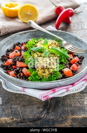 Pesto - verkrusteten Kabeljau mit Puy Linsen und Tomaten in eine Schüssel geben. Stockfoto