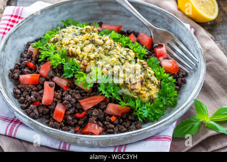 Pesto - verkrusteten Kabeljau mit Puy Linsen und Tomaten in eine Schüssel geben. Stockfoto