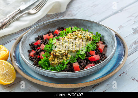 Pesto - verkrusteten Kabeljau mit Puy Linsen und Tomaten in eine Schüssel geben. Stockfoto