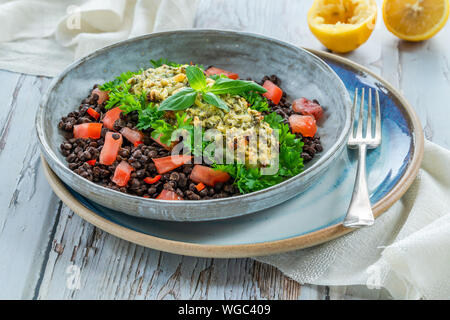Pesto - verkrusteten Kabeljau mit Puy Linsen und Tomaten in eine Schüssel geben. Stockfoto