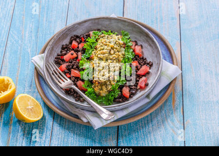 Pesto - verkrusteten Kabeljau mit Puy Linsen und Tomaten in eine Schüssel geben. Stockfoto