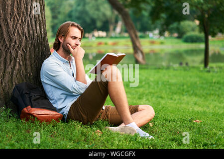 Ernster Kursteilnehmer im Park Campus ein Buch lesen. Stockfoto