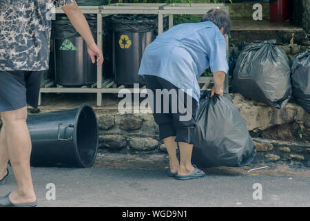 Weibliche Arbeitnehmer den Müll sortieren und in schwarzen Beutel für den Transport praktisch verpackt. Stockfoto