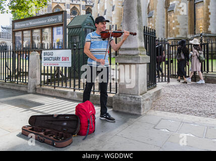 Street Entertainer, Straßenmusiker oder Gaukler Spielen der Violine, Straßenmusik außerhalb der Westminster Abbey in Westminster, London, England, UK. Geiger. Stockfoto
