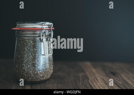 Nahaufnahme von Chia Samen in Glas weck jar auf hölzernen Tisch gegen den dunklen Hintergrund Stockfoto