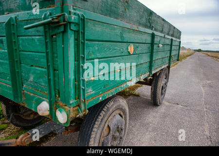 Die grüne alte landwirtschaftliche Anhänger auf den Asphalt. Die Zeit der Ernte Stockfoto