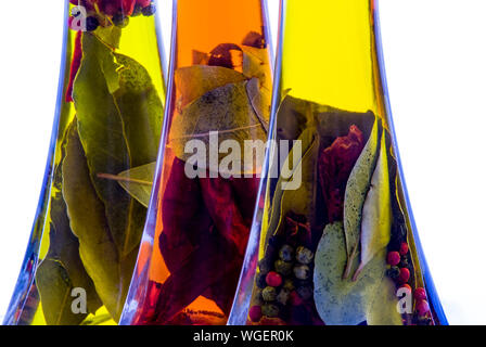 High key Schuß von drei Flaschen Olivenöl mit gemischten Kräutern und Gewürzen infundiert. Stockfoto