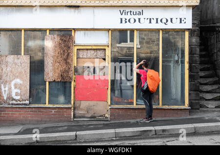 Weibliche Wanderer Haar kämmen im Fenster der Verbrettert Friseure in Loftus, North East England. Großbritannien Stockfoto