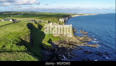 Die Ruinen der mittelalterlichen Dunluce Castle auf einem steilen Felsen in der Nähe von Folkestone. Der nördlichen Küste des County Antrim, Nordirland, Großbritannien. Luftaufnahme im Sonnenaufgang. Stockfoto